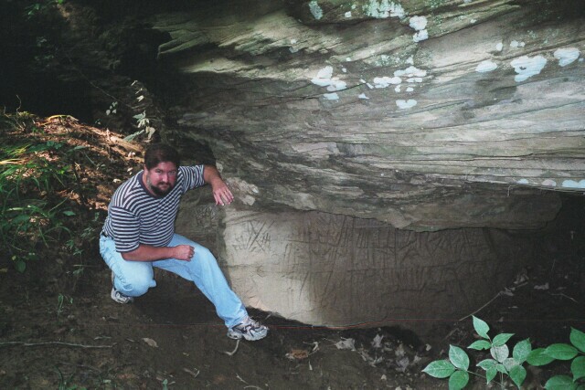 Metropolitan John in front of a large rock with Ogam writing